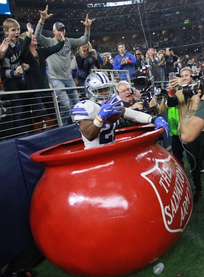 Dallas Cowboys running back Ezekiel Elliott (21) jumps into the Salvation Army red kettle after scoring a second quarter touchdown against the Tampa Bay Buccaneers on Sunday, Dec. 18, 2016 at AT&T Stadium in Arlington, Texas. 