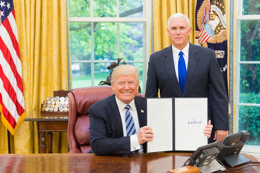 President Trump, joined by Vice President Mike Pence, displays a signed executive action order.