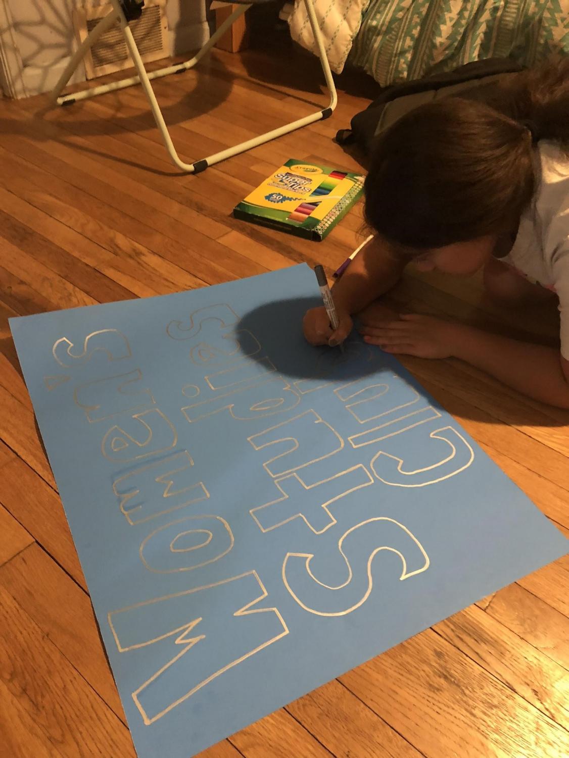 Senior Liz Corpus designs a poster for Women's Studies Club. The club will be featured at the school's Club Fair on Aug. 31.