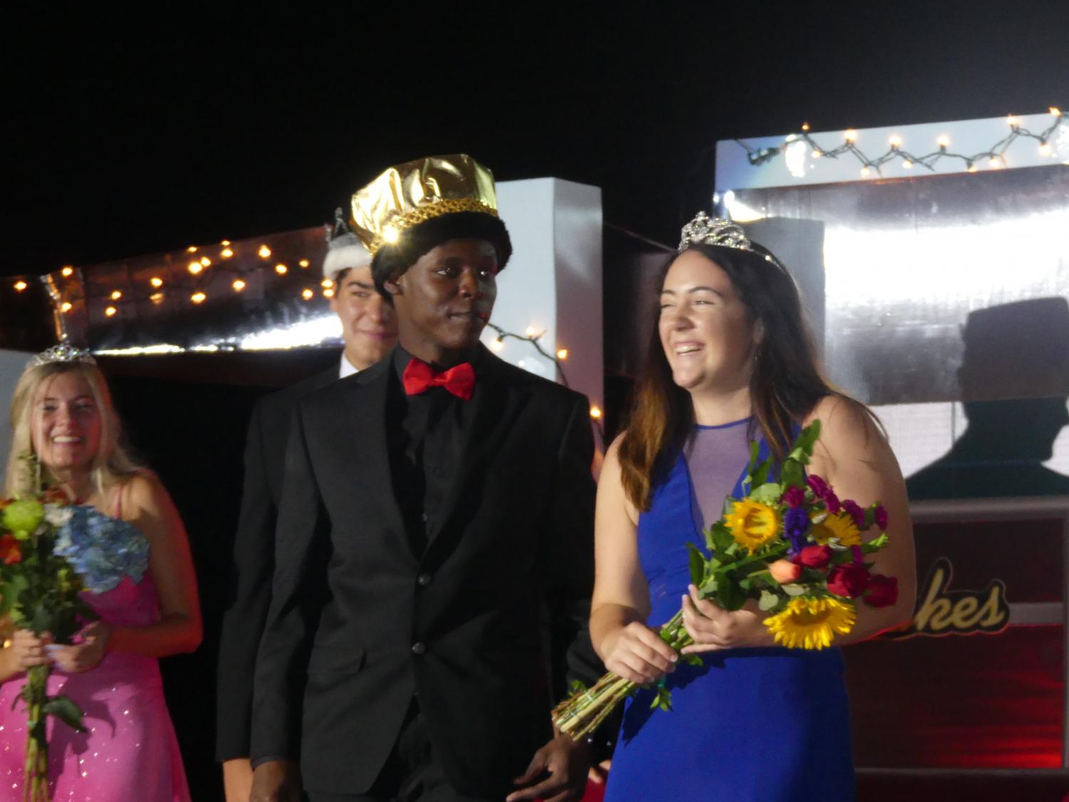 Stacy Collins and Bailey Ross enjoy the loud applause from the audience in the Wood Gym. Behind them stands 2018 Princess Hannah Bright and 2017 King John Catalano.