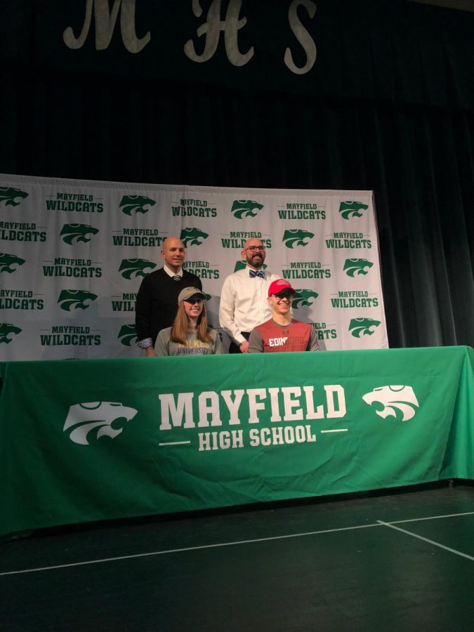 Keith Leffler and Jeffrey Legan stand behind senior signees during signing day.
