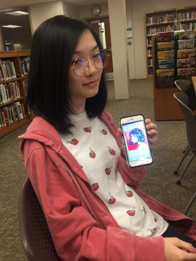 Moy shows off a phone image of her artwork.
