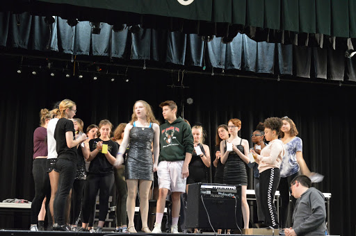 The cast rehearses the song “They Both Reached for the Gun” in partial costume.  Morgan Beck, center, is excited about the performances that start on Thursday.  She said, “Expect a fun show full of crazy twists and turns. The world of Chicago is full of murder, adultery, love, and loss therefore who wouldn’t want to come see it?”