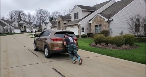 Sophomore Dylan Gamber has been creative with his strength training, as he pushes a car near his home.
