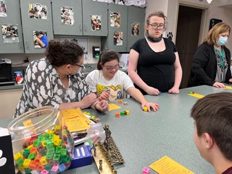 Speech-Language Pathologist Danielle Kallmeyer plays the dreidel game with  Kathleen Morgans special education students. Morgan appreciates how in-depth Kallmeyer is with the history of Hanukkah. Morgan said, “Sometimes its just the game or other times she talks about the symbolism and the story behind Hanukkah.” 