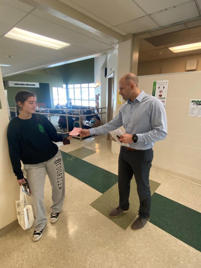 During lunch, hall monitor Josh Hayes issues a pink hall pass to senior Emma Buda.