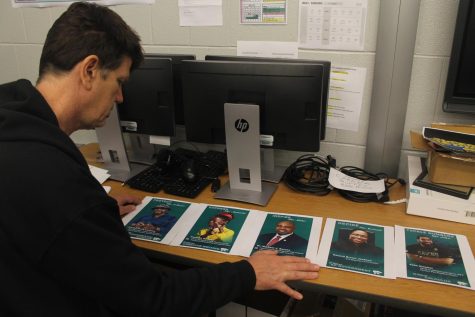Excel TECC teacher Michael Caldwell lays out the newly printed designs for Black History Month posters in his classroom. A total of 11 posters will be displayed outside the main office.