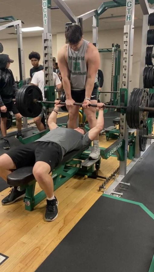 As part of their off-season workouts, junior Joe Barch bench presses, while Luke Durosko spots for him in the weight room.