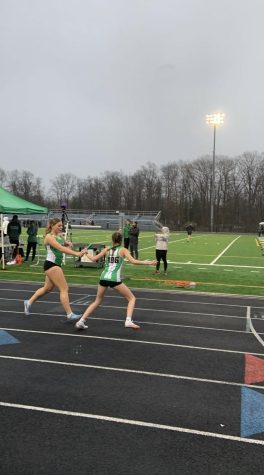 At one of their home meets, Taylor Arth participates in a relay where she receives the baton from teammate Brynlee Stoll.
